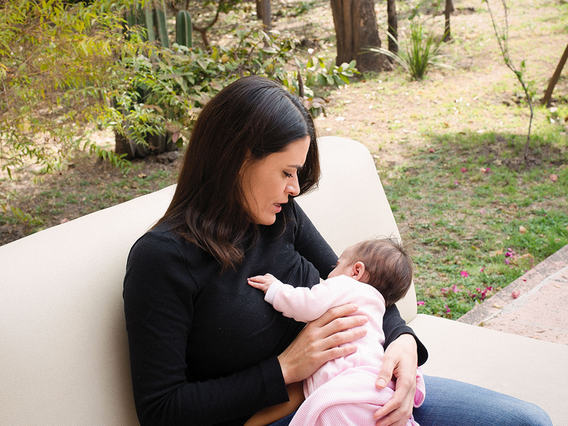 Imagen de una mujer embarazada sentada en el suelo: Mujer embarazada sentada en el suelo con una mano en su vientre, simbolizando la preparación y conexión emocional durante el embarazo.