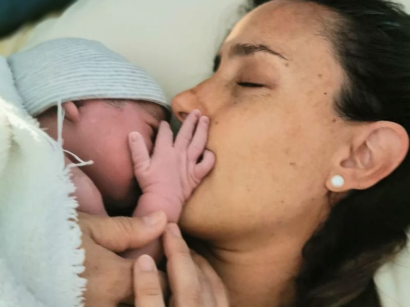 Imagen de un bebé sonriente con un gran lazo en la cabeza: Bebé sonriente con un gran lazo blanco en la cabeza, representando la alegría y el resultado positivo de una preparación adecuada para el nacimiento.