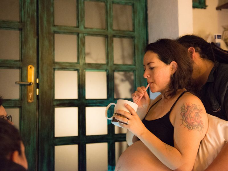 Imagen de una mujer embarazada sentada en el suelo: Mujer embarazada sentada en el suelo con una mano en su vientre, simbolizando la preparación y conexión emocional durante el embarazo.