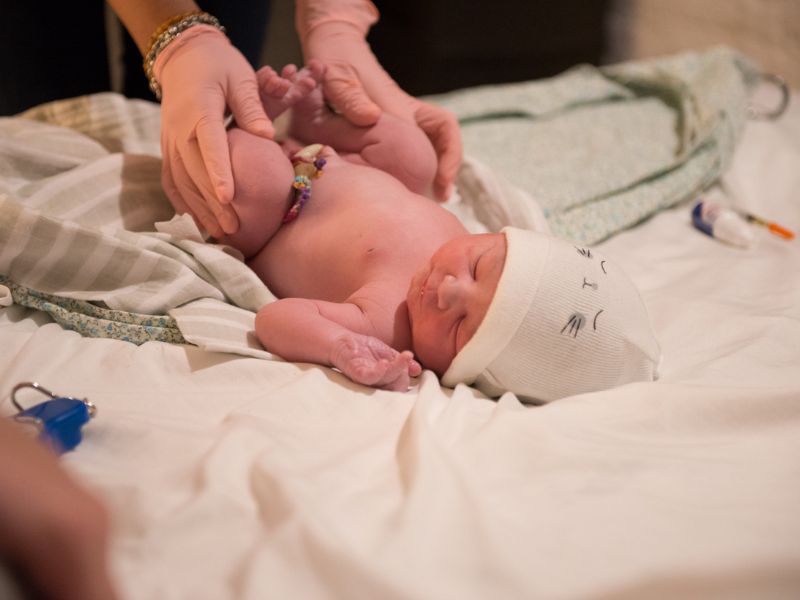 Imagen de un bebé sonriente con un gran lazo en la cabeza: Bebé sonriente con un gran lazo blanco en la cabeza, representando la alegría y el resultado positivo de una preparación adecuada para el nacimiento.