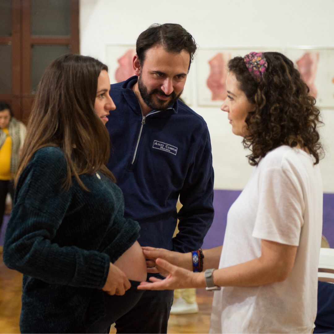 Imagen de una pareja sonriente durante el curso prenatal: Pareja sonriente participando en el curso psicoprofiláctico, mostrando la importancia del apoyo mutuo y la preparación conjunta para el parto.