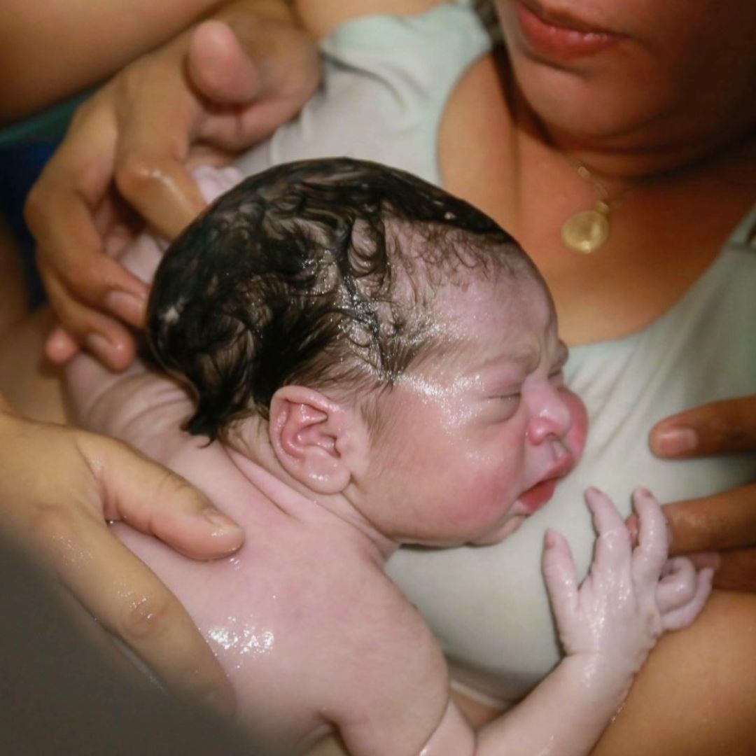 Imagen de un bebé sonriente con un gran lazo en la cabeza: Bebé sonriente con un gran lazo blanco en la cabeza, representando la alegría y el resultado positivo de una preparación adecuada para el nacimiento.