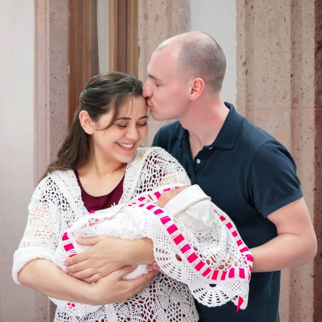 Pareja mostrando un cartel decorado con imágenes y símbolos relacionados con el embarazo y la maternidad, parte de una actividad creativa del curso prenatal psicoprofiláctico.
