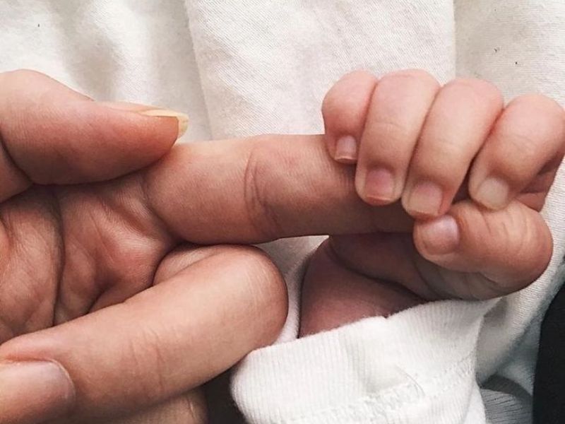 Imagen de un bebé sonriente con un gran lazo en la cabeza: Bebé sonriente con un gran lazo blanco en la cabeza, representando la alegría y el resultado positivo de una preparación adecuada para el nacimiento.