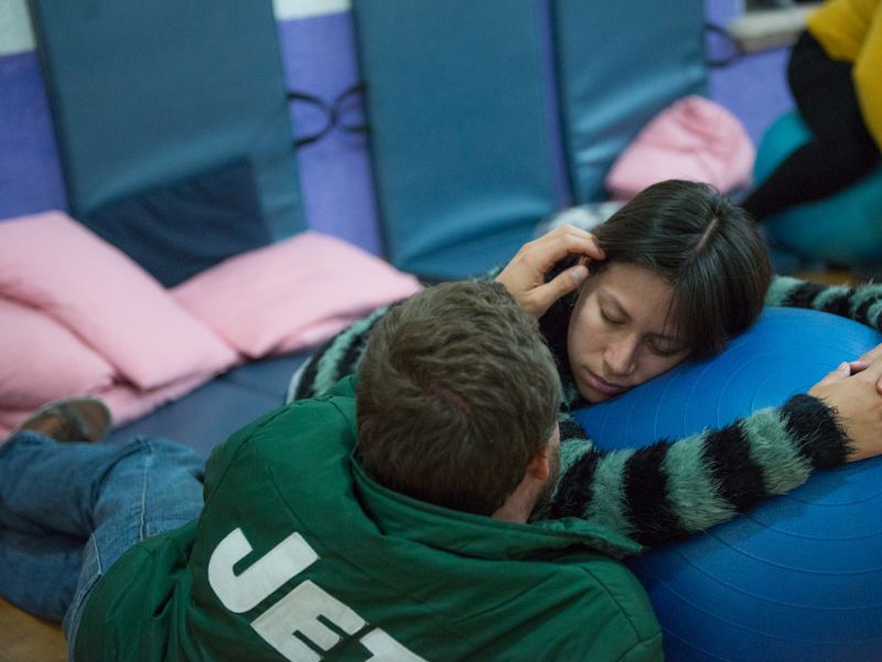 Imagen de una mujer embarazada sentada en el suelo: Mujer embarazada sentada en el suelo con una mano en su vientre, simbolizando la preparación y conexión emocional durante el embarazo.