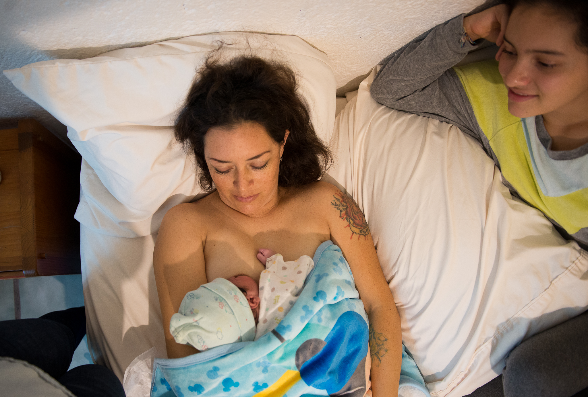 Imagen de una mujer embarazada sentada en el suelo: Mujer embarazada sentada en el suelo con una mano en su vientre, simbolizando la preparación y conexión emocional durante el embarazo.